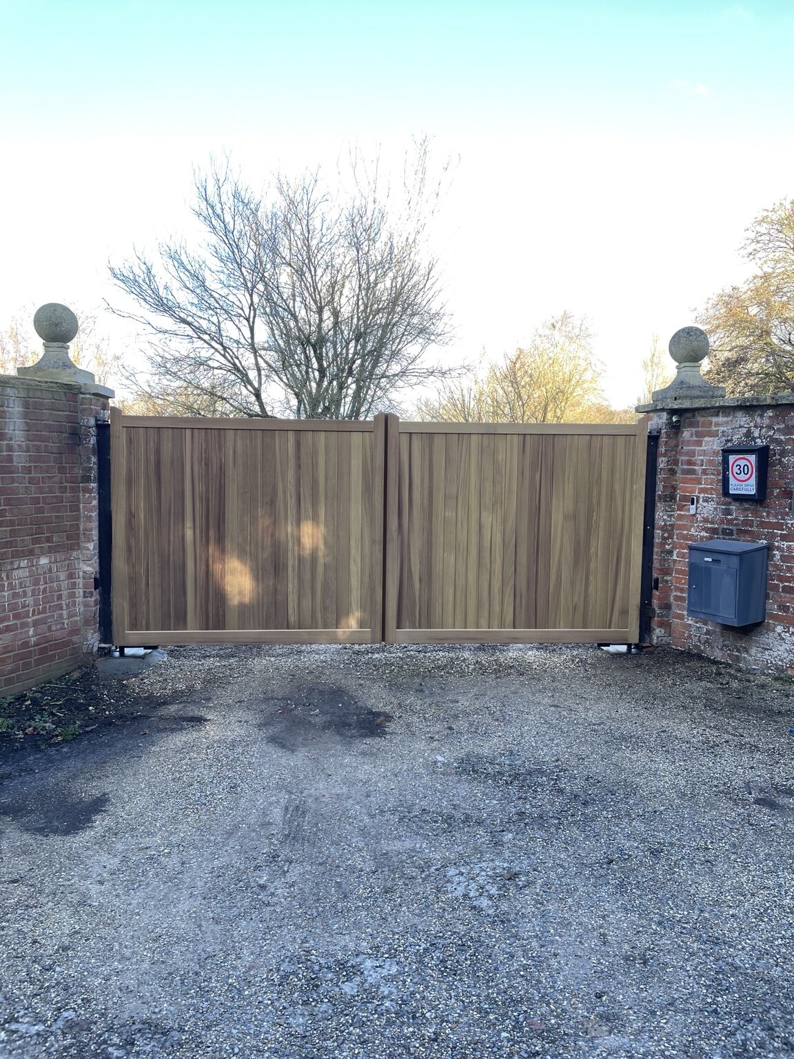 Timber driveway gates between brick pillars viewed from outside